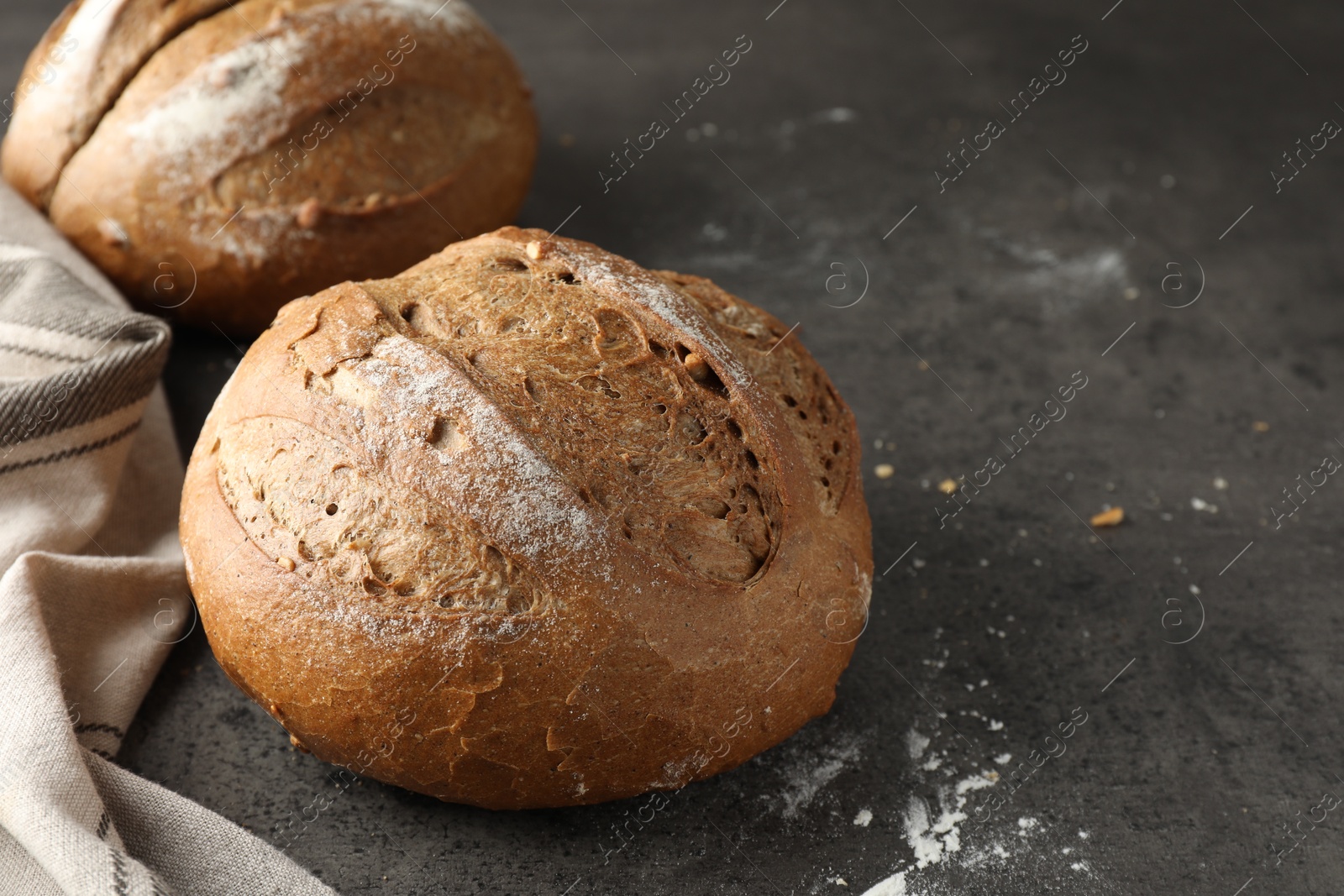 Photo of Freshly baked bread loafs on grey table, closeup. Space for text