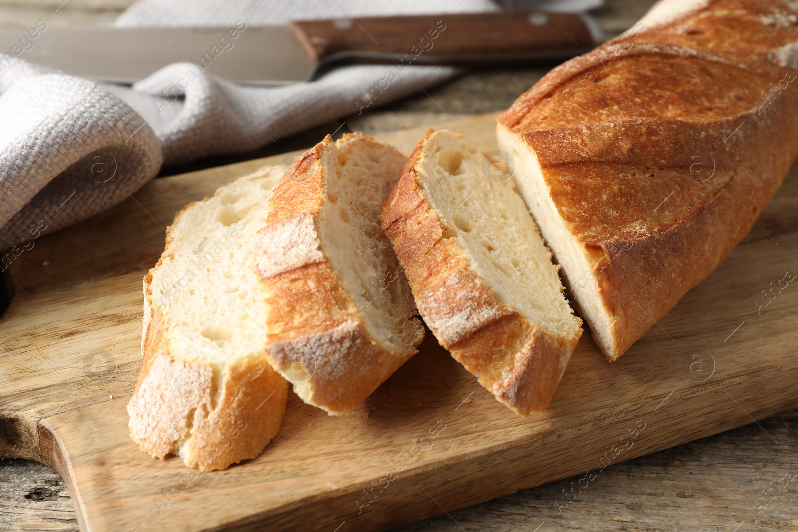 Photo of Pieces of fresh baguette on wooden table, closeup