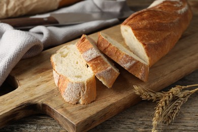 Photo of Pieces of fresh baguette and spikes on wooden table, closeup