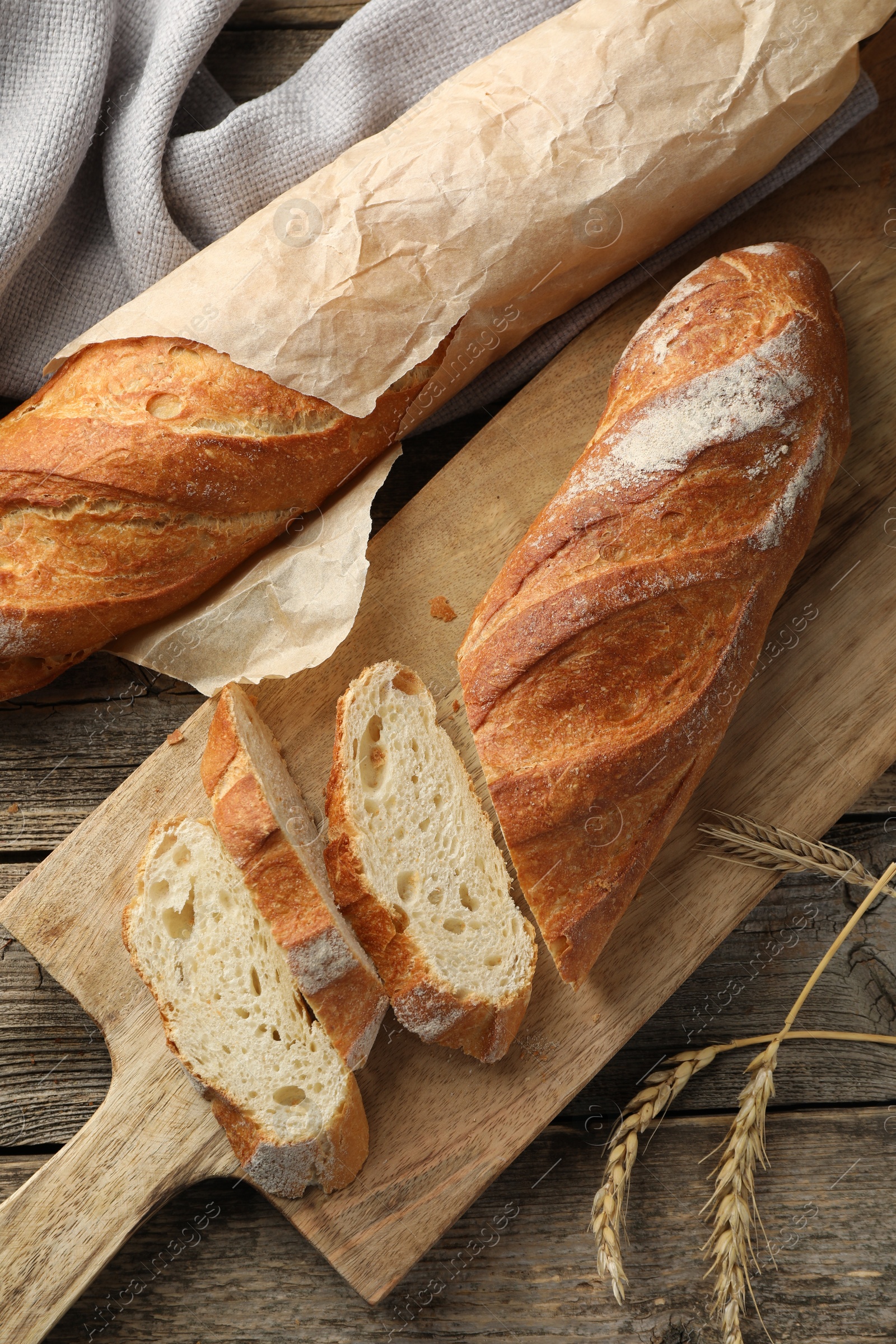 Photo of Fresh baguettes and spikes on wooden table, flat lay