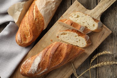 Photo of Fresh baguettes and spikes on wooden table, flat lay