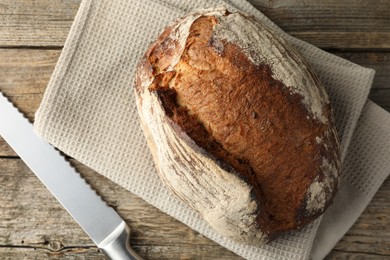 Photo of Freshly baked bread and knife on wooden table, top view