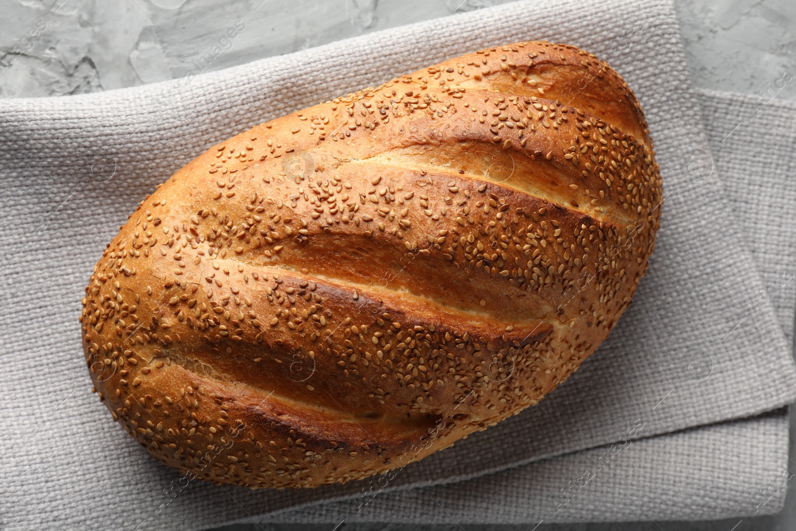 Photo of Freshly baked bread with seeds on grey table, top view