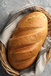 Photo of Freshly baked bread in wicker basket on grey table, top view