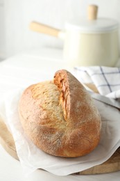 Photo of Loaf of delicious bread on white wooden table. Space for text