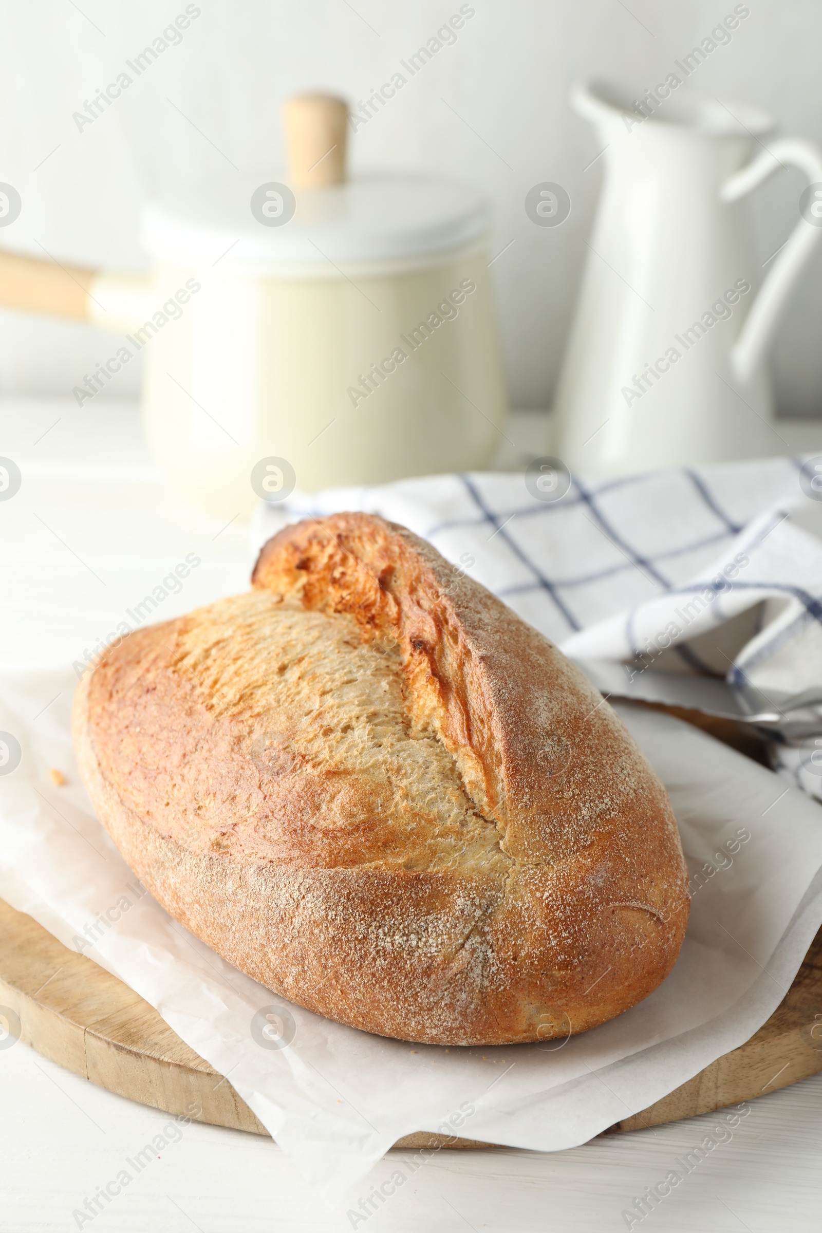 Photo of Loaf of delicious bread on white wooden table. Space for text