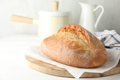 Photo of Loaf of delicious bread on white wooden table. Space for text