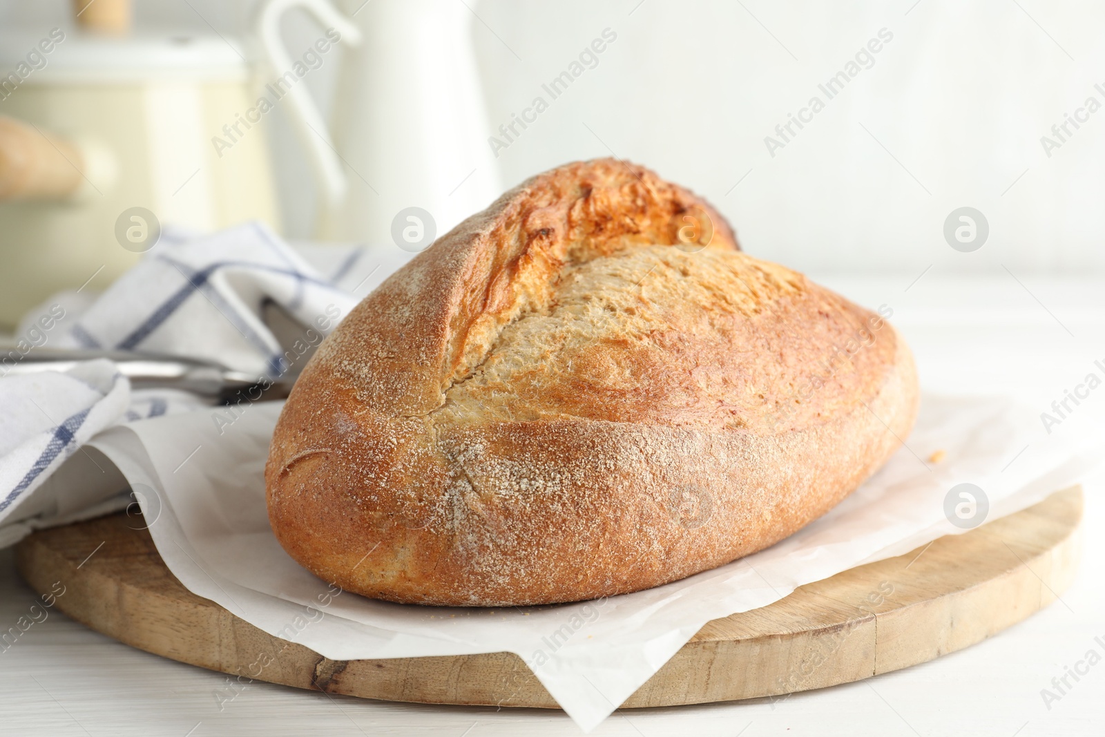 Photo of Loaf of delicious bread on white wooden table, closeup