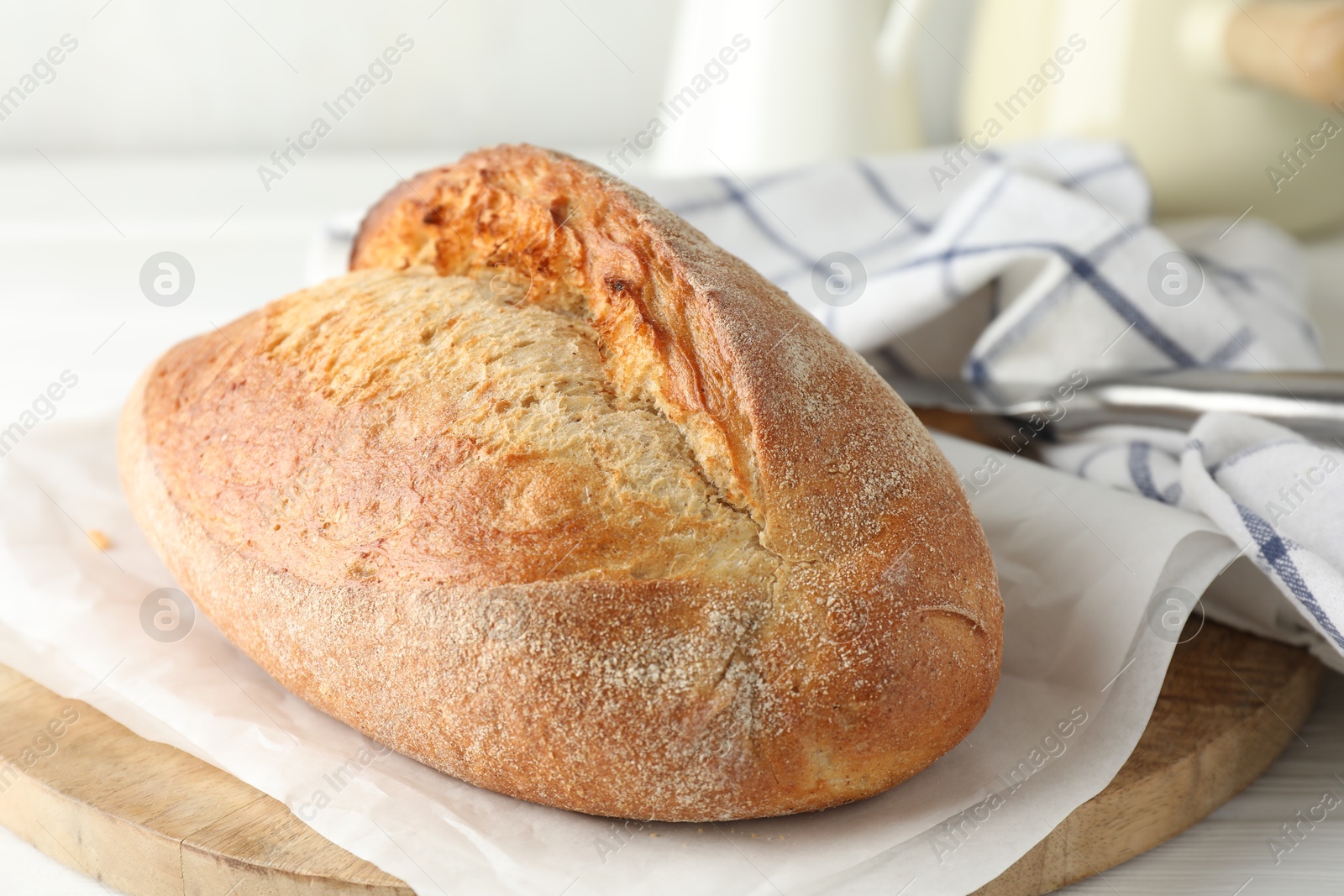 Photo of Loaf of delicious bread on white wooden table, closeup