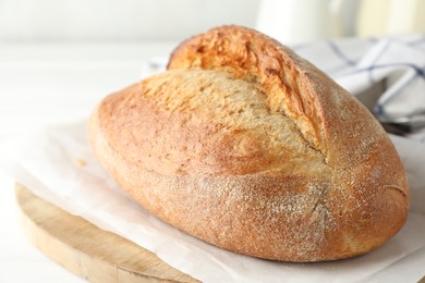 Photo of Loaf of delicious bread on white wooden table, closeup