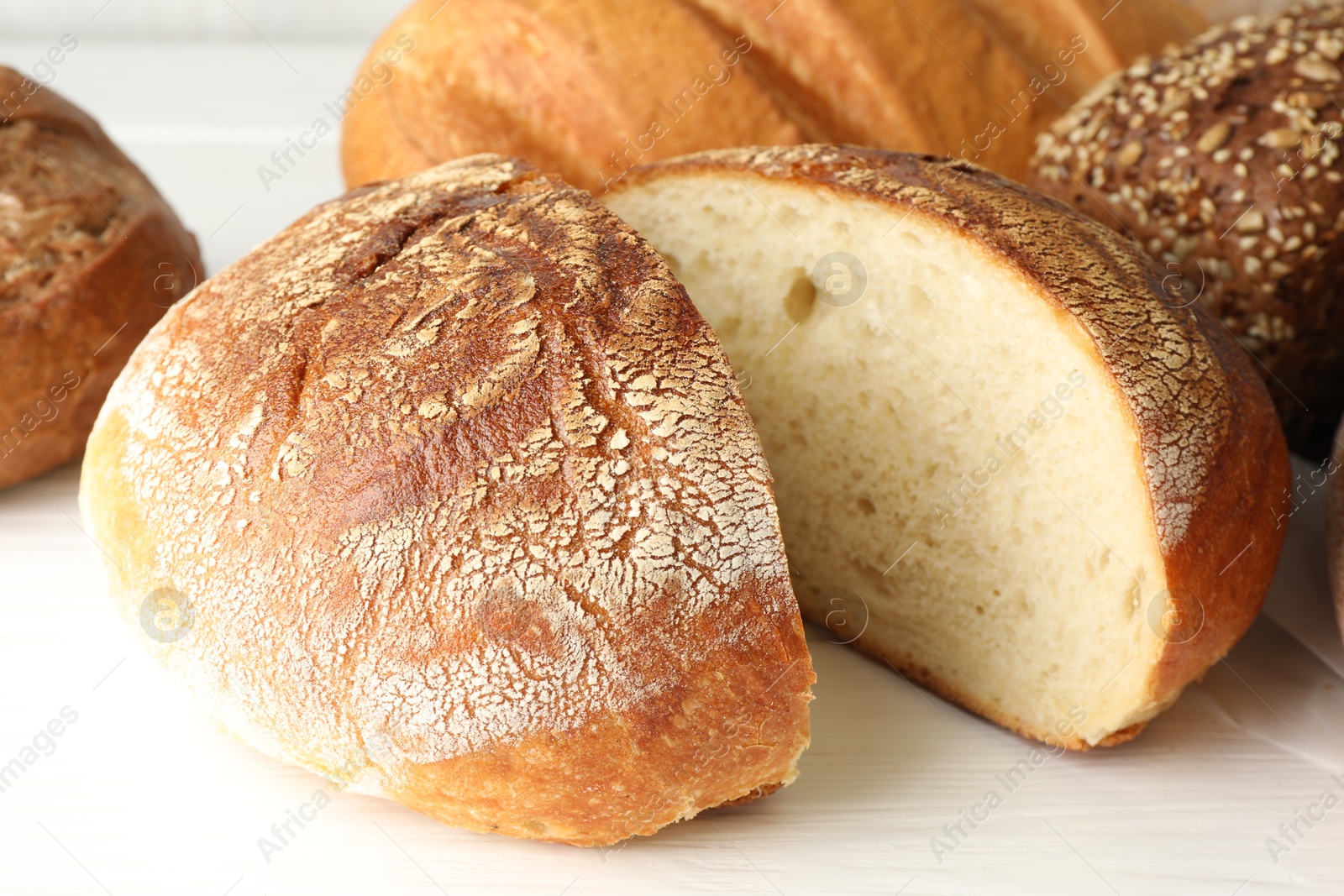 Photo of Cut loaf of freshly baked bread on white table, closeup