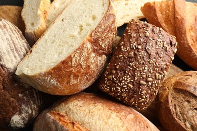 Whole and cut loafs of bread on table, closeup