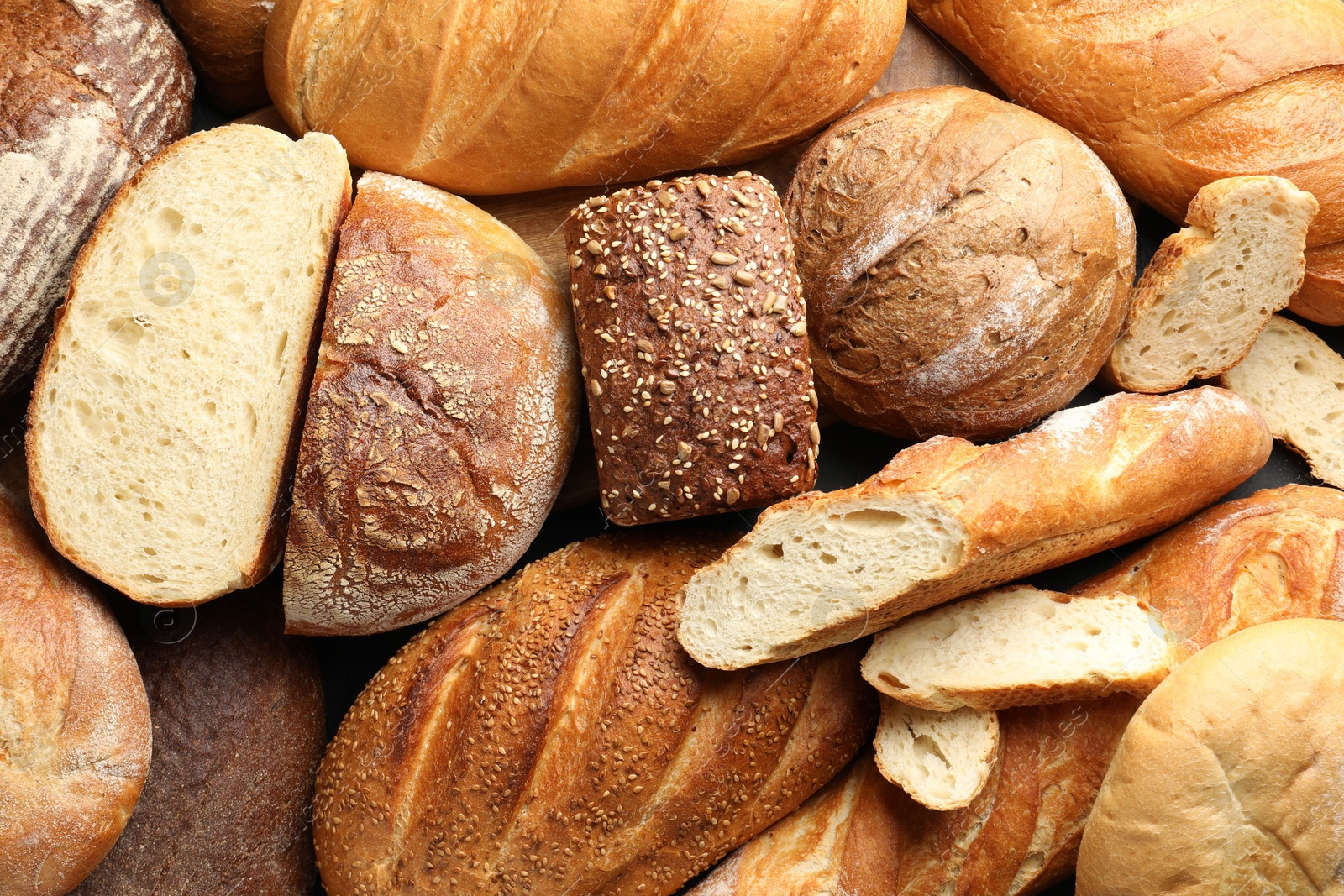 Photo of Whole and cut loafs of bread on table, closeup