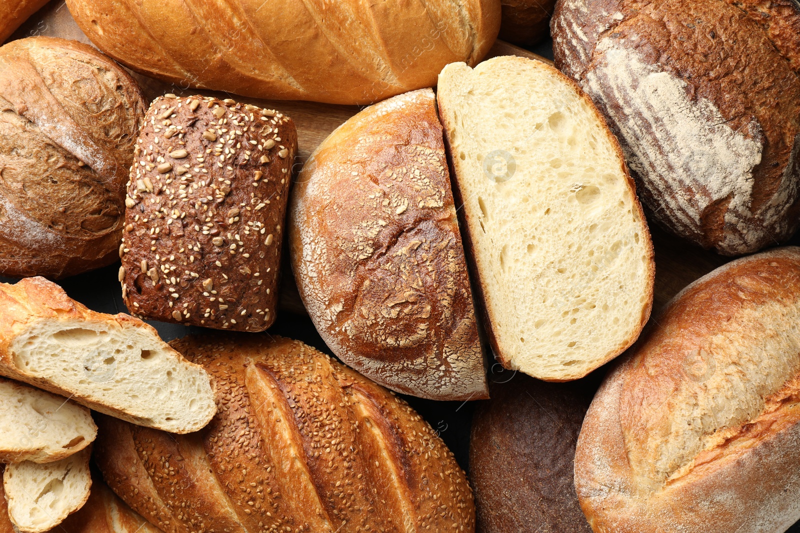 Photo of Whole and cut loafs of bread on table, closeup