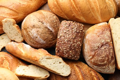 Photo of Whole and cut loafs of bread on table, closeup