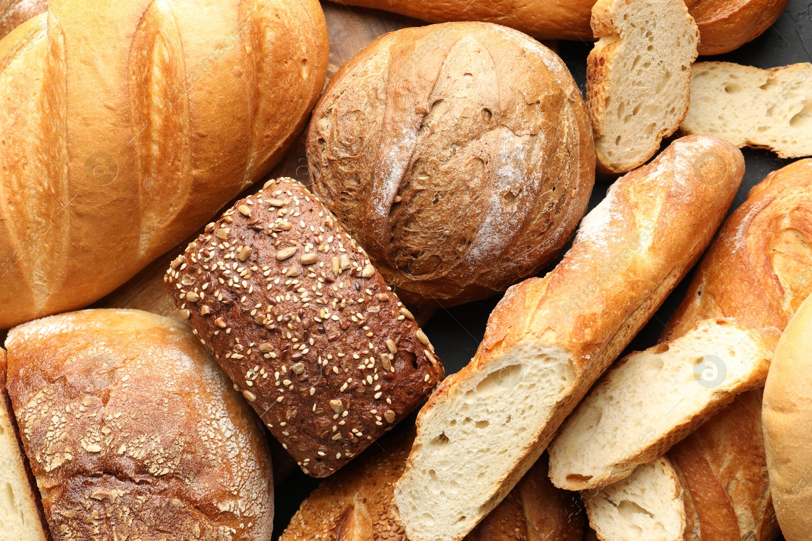 Photo of Whole and cut loafs of bread on table, closeup