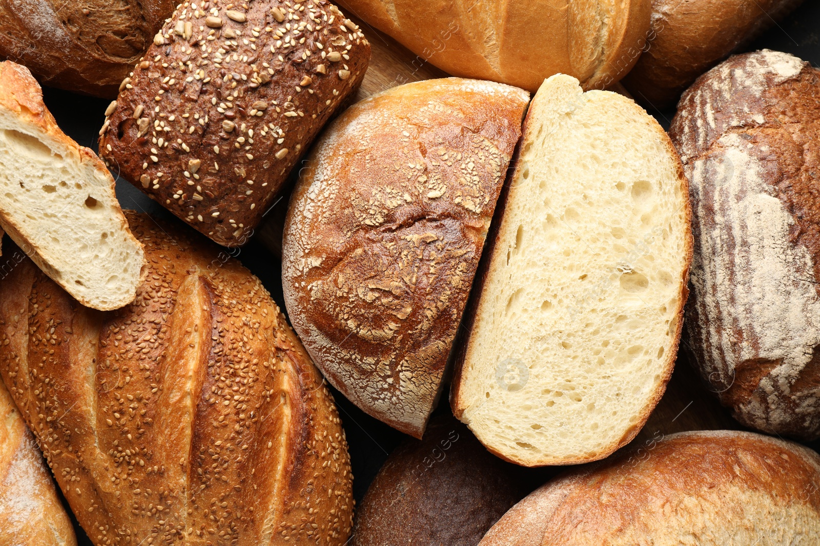 Photo of Whole and cut loafs of bread on table, closeup