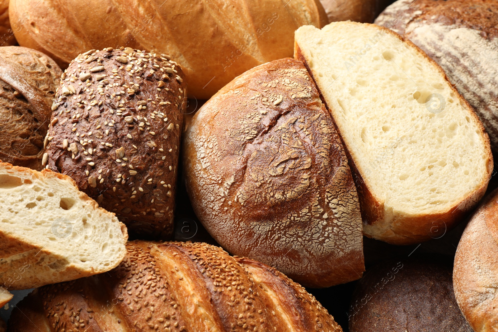 Photo of Whole and cut loafs of bread on table, closeup