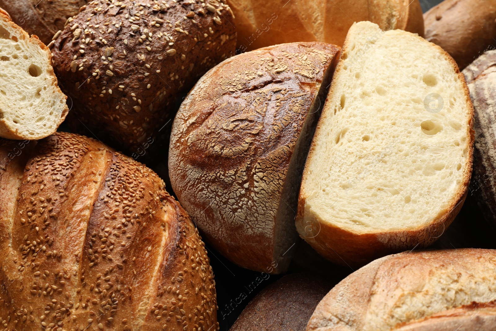 Photo of Whole and cut loafs of bread on table, closeup