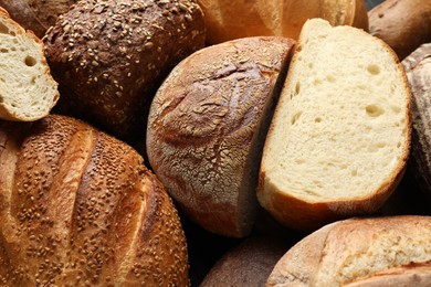 Whole and cut loafs of bread on table, closeup