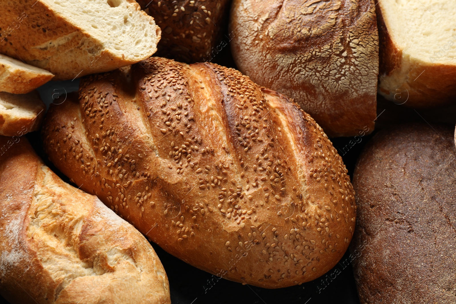 Photo of Whole and cut loafs of bread on table, closeup