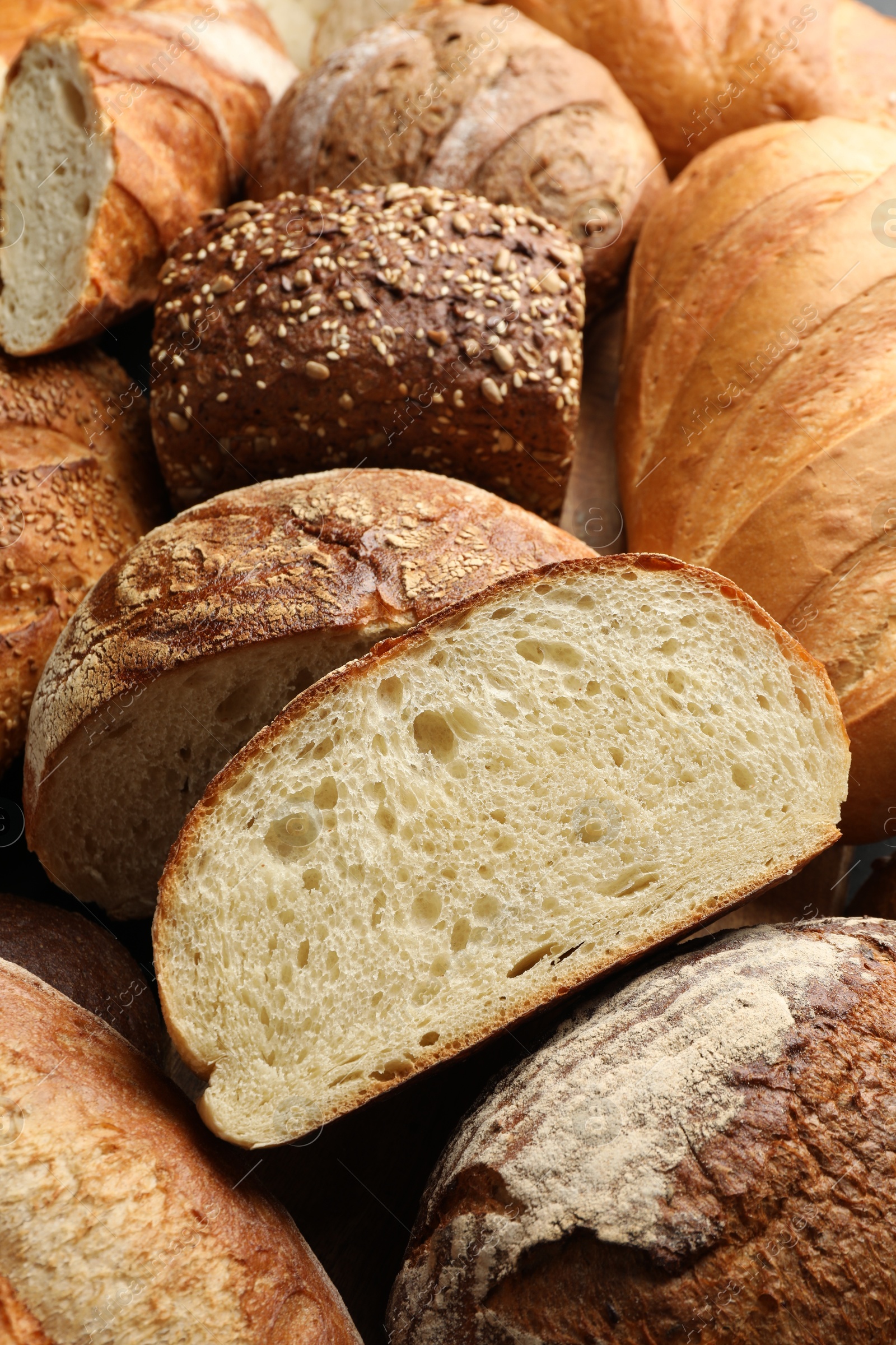 Photo of Whole and cut loafs of bread on table, closeup