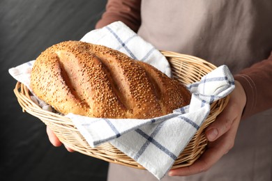 Photo of Woman with loaf of freshly baked bread on black background, closeup