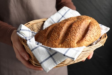 Photo of Woman with loaf of freshly baked bread on black background, closeup