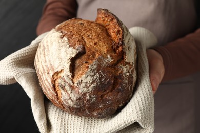 Photo of Woman with loaf of freshly baked bread on black background, closeup