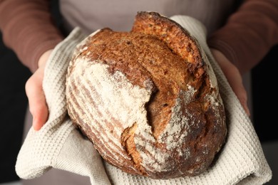 Photo of Woman with loaf of freshly baked bread on black background, closeup