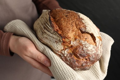 Photo of Woman with loaf of freshly baked bread on black background, closeup