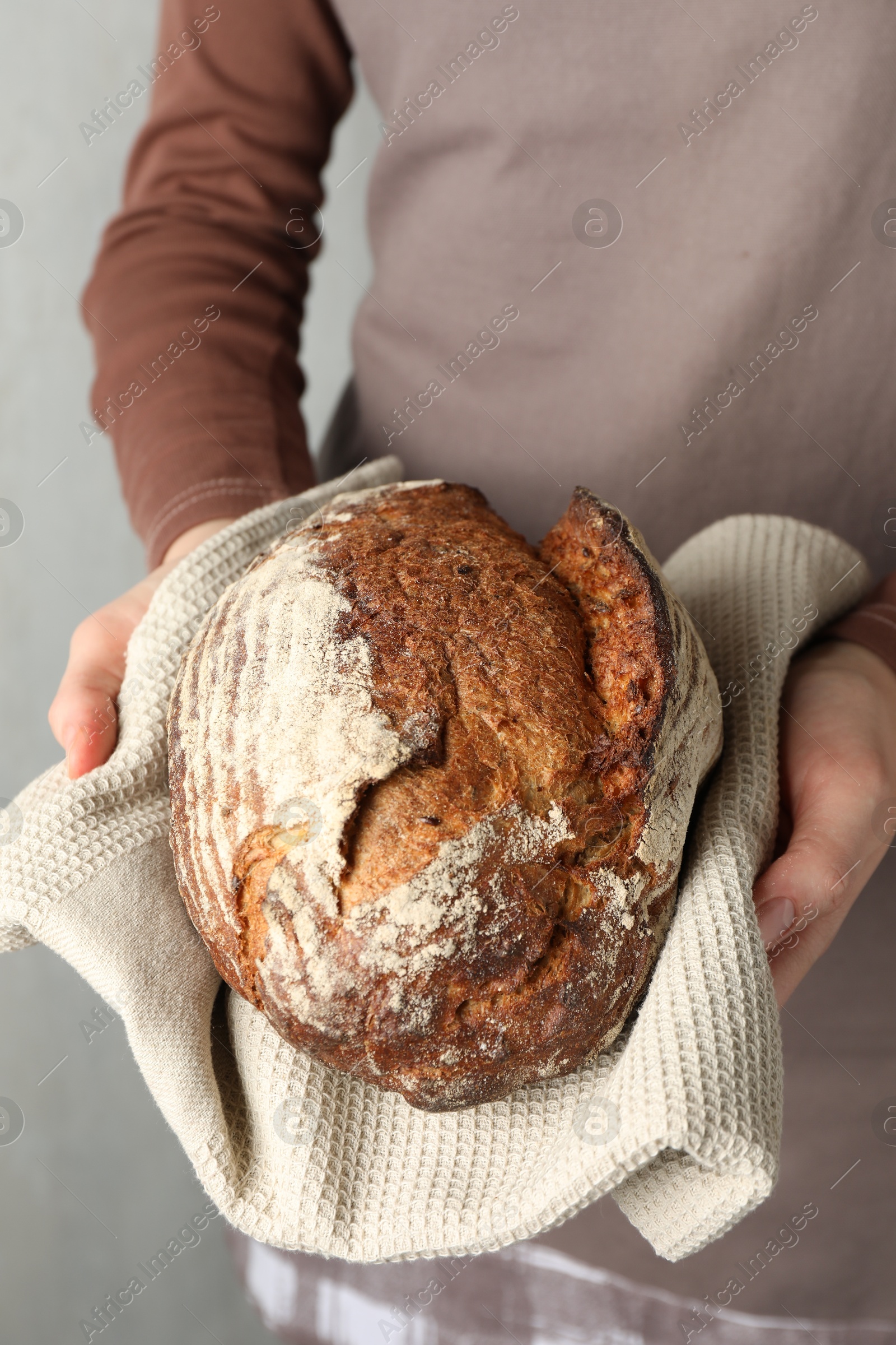 Photo of Woman with loaf of freshly baked bread on light background, closeup