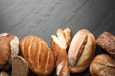 Photo of Loafs of different bread on black background, flat lay. Space for text