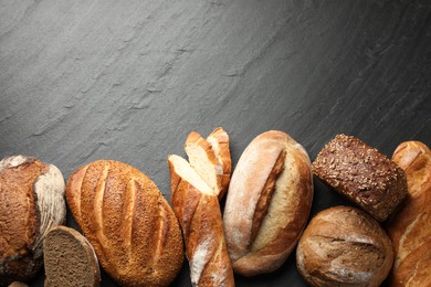 Photo of Loafs of different bread on black background, flat lay. Space for text