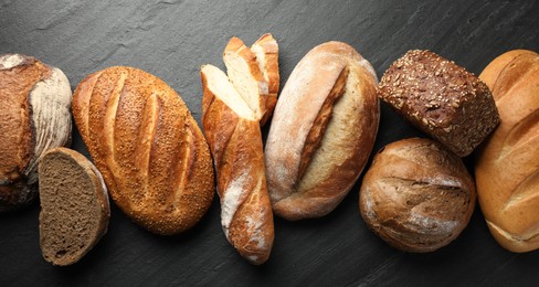 Photo of Loafs of different bread on black background, flat lay