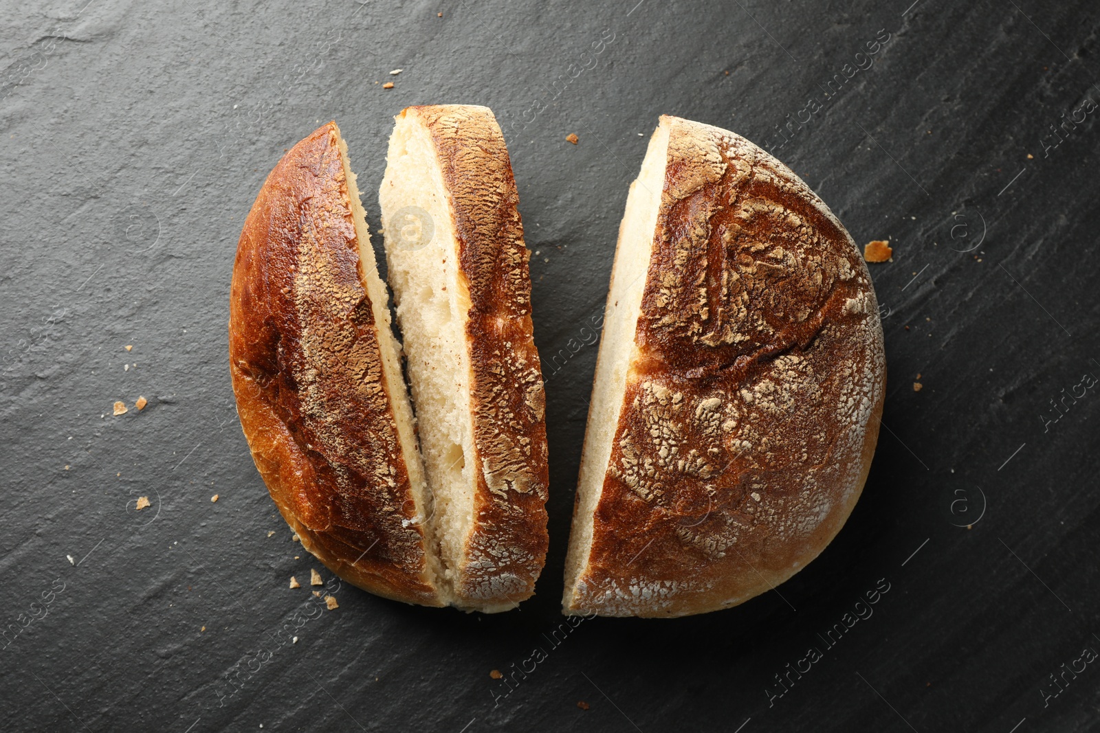 Photo of Cut loaf of fresh bread on black background, top view