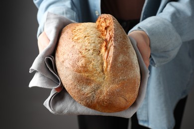 Photo of Woman with loaf of freshly baked bread on grey background, closeup