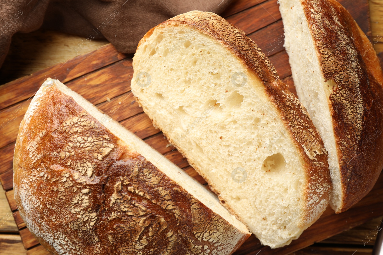 Photo of Cut loaf of fresh bread on wooden table, closeup