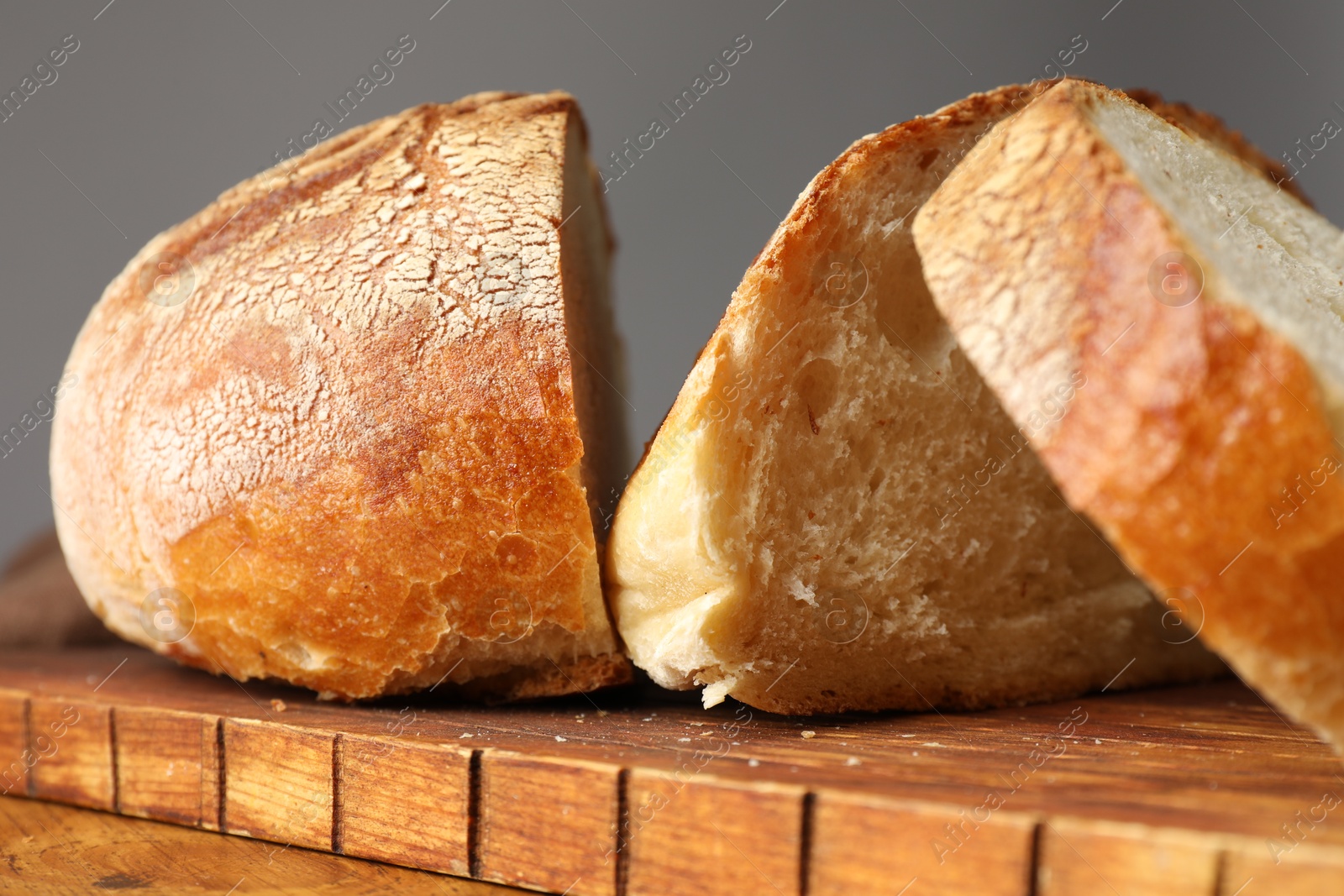 Photo of Cut loaf of fresh bread on wooden table, closeup