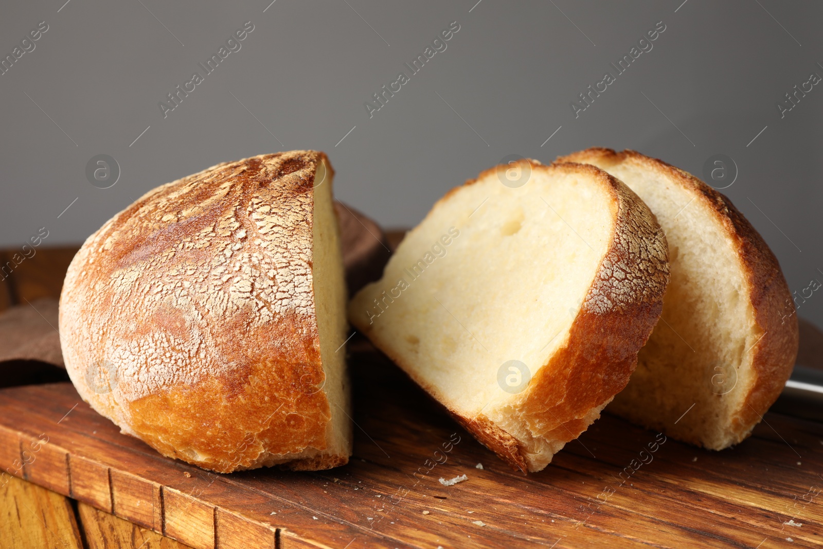 Photo of Cut loaf of fresh bread on wooden table, closeup