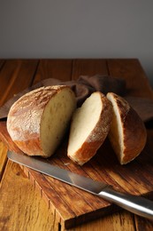 Photo of Cut loaf of fresh bread and knife on wooden table