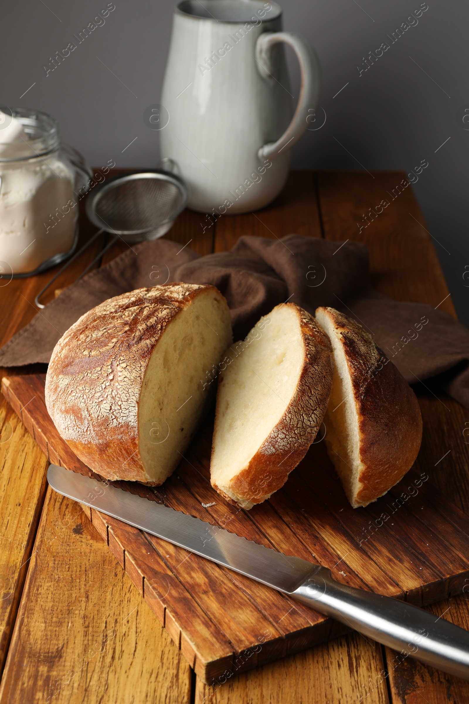 Photo of Cut loaf of fresh bread and knife on wooden table