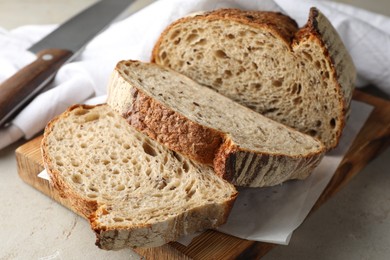 Photo of Cut loaf of fresh bread and knife on table, closeup