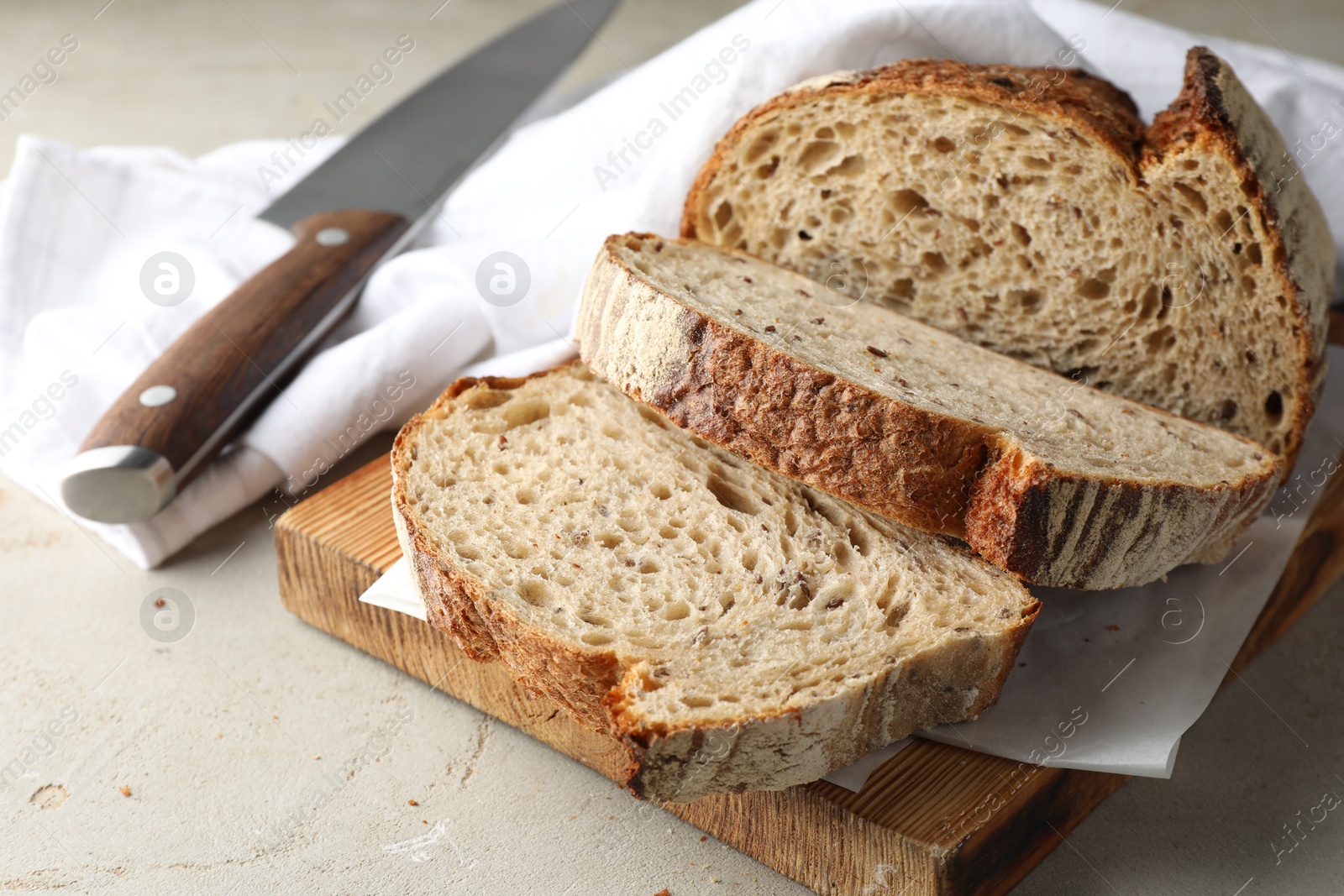 Photo of Cut loaf of fresh bread and knife on table, closeup