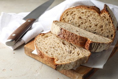 Photo of Cut loaf of fresh bread and knife on table, closeup