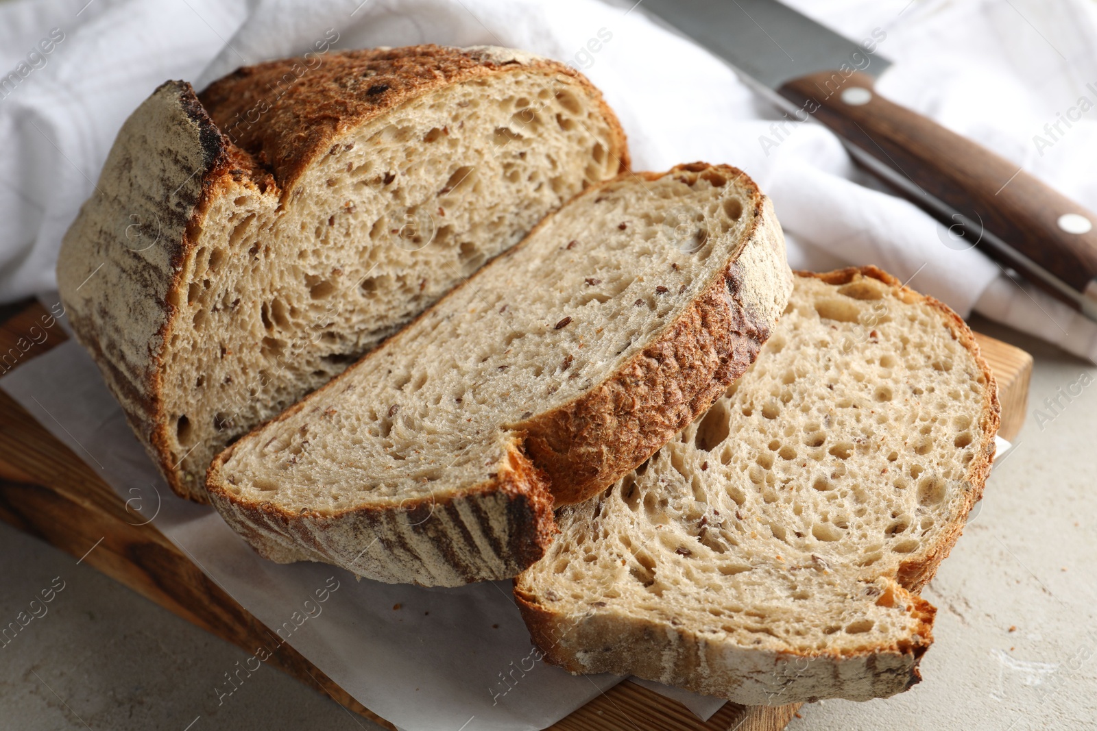 Photo of Cut loaf of fresh bread and knife on table, closeup