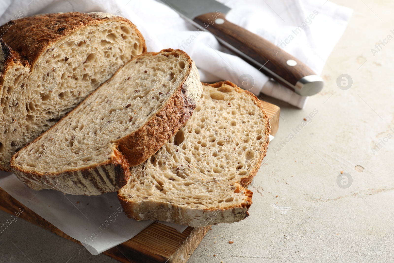 Photo of Cut loaf of fresh bread and knife on table, closeup