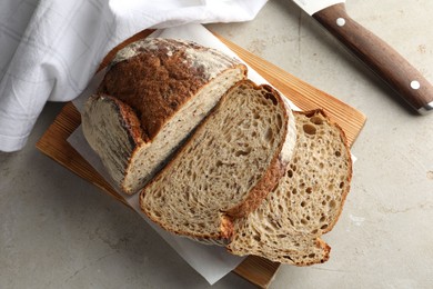 Photo of Cut loaf of fresh bread and knife on table, top view