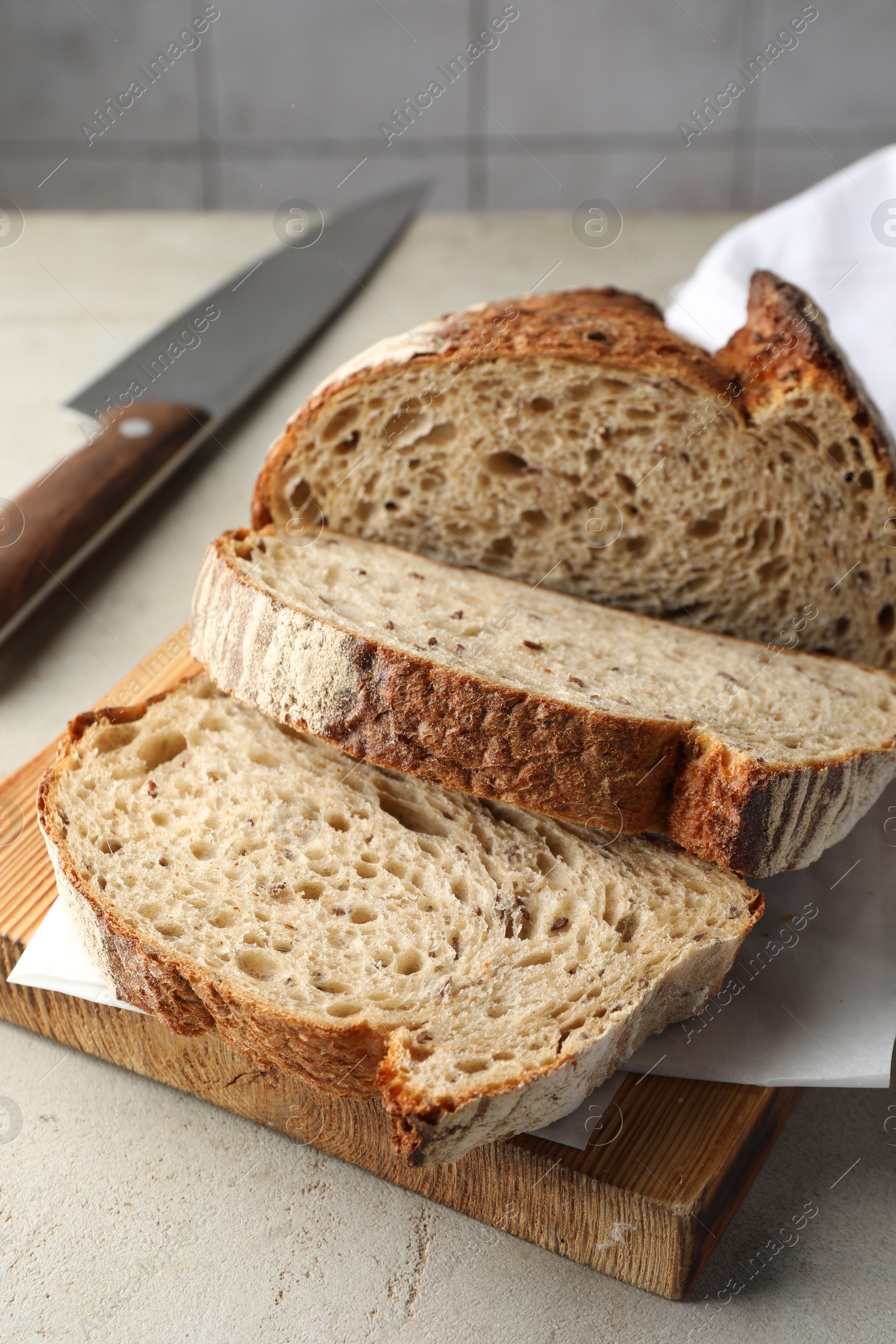 Photo of Cut loaf of fresh bread and knife on table, closeup