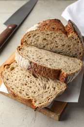 Photo of Cut loaf of fresh bread and knife on table, closeup